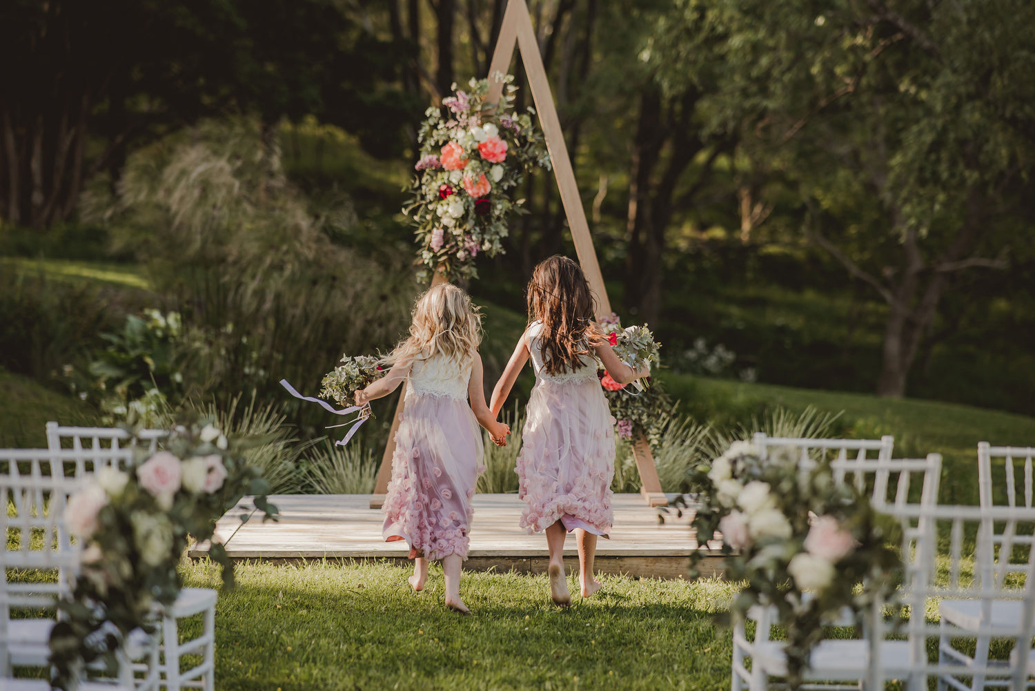 Flower girls running towards wedding arch