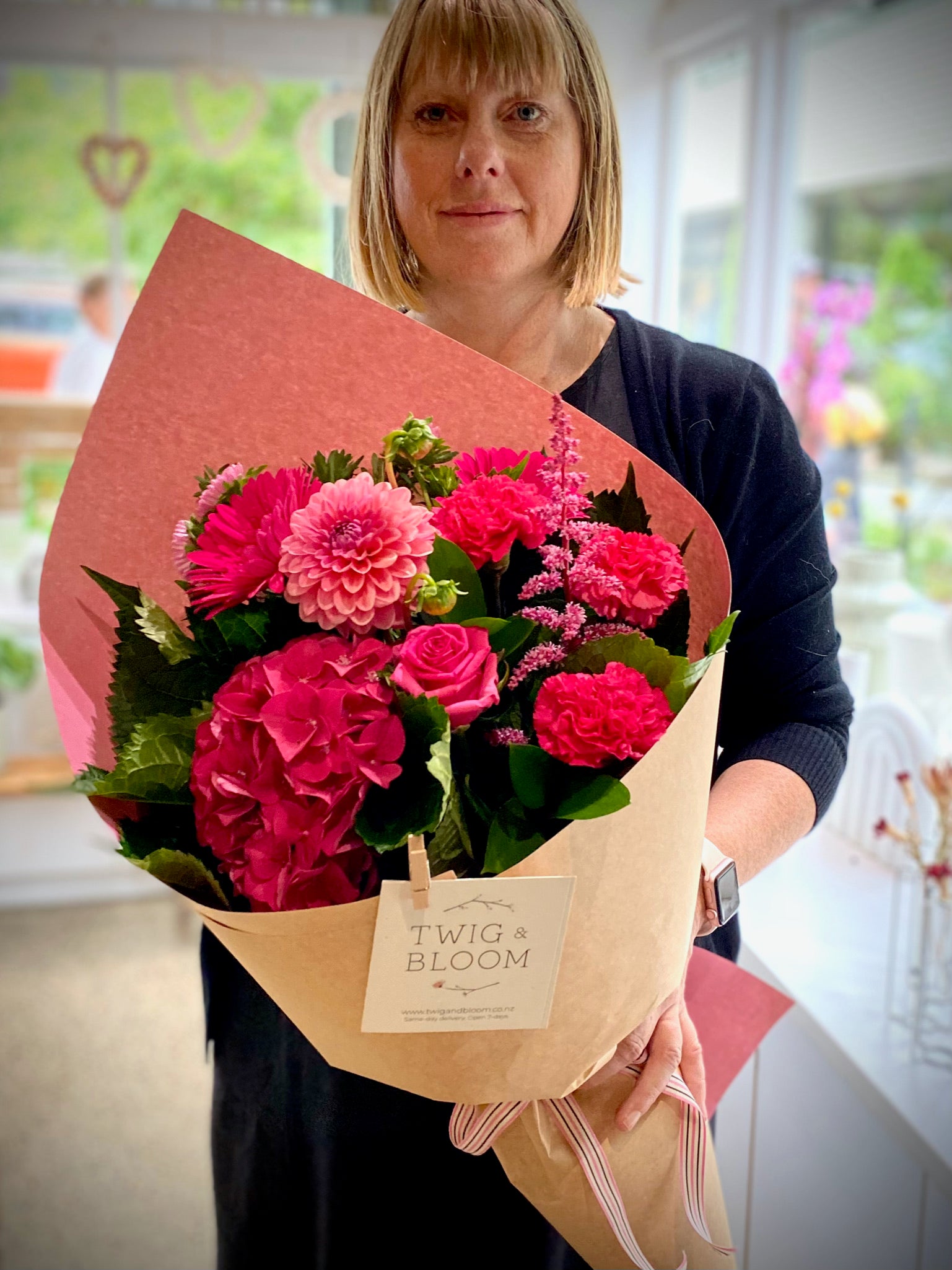 Woman holding a pink fresh flower bouquet with a sustainable wrap