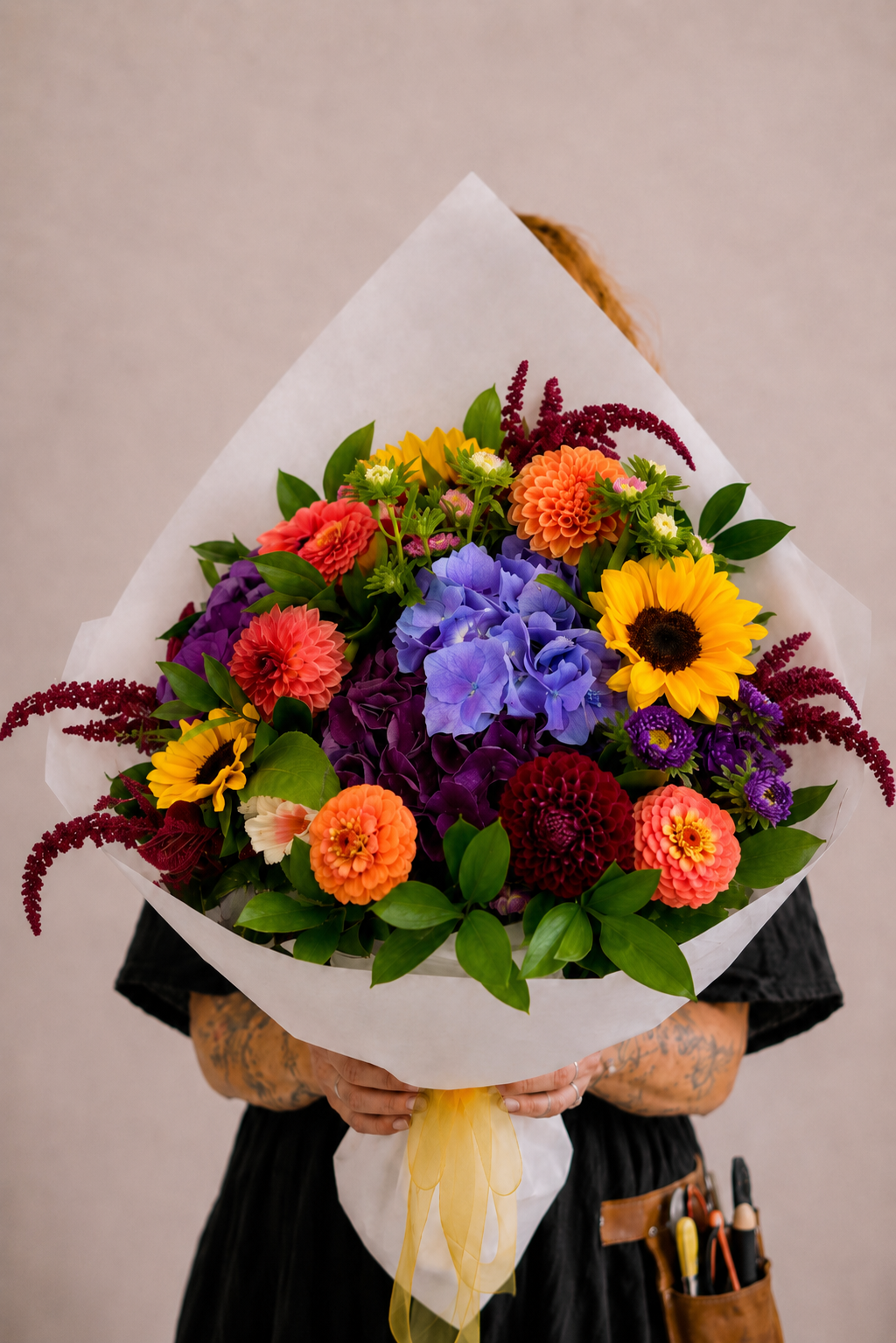 Person holding a colorful bouquet of flowers against a neutral background