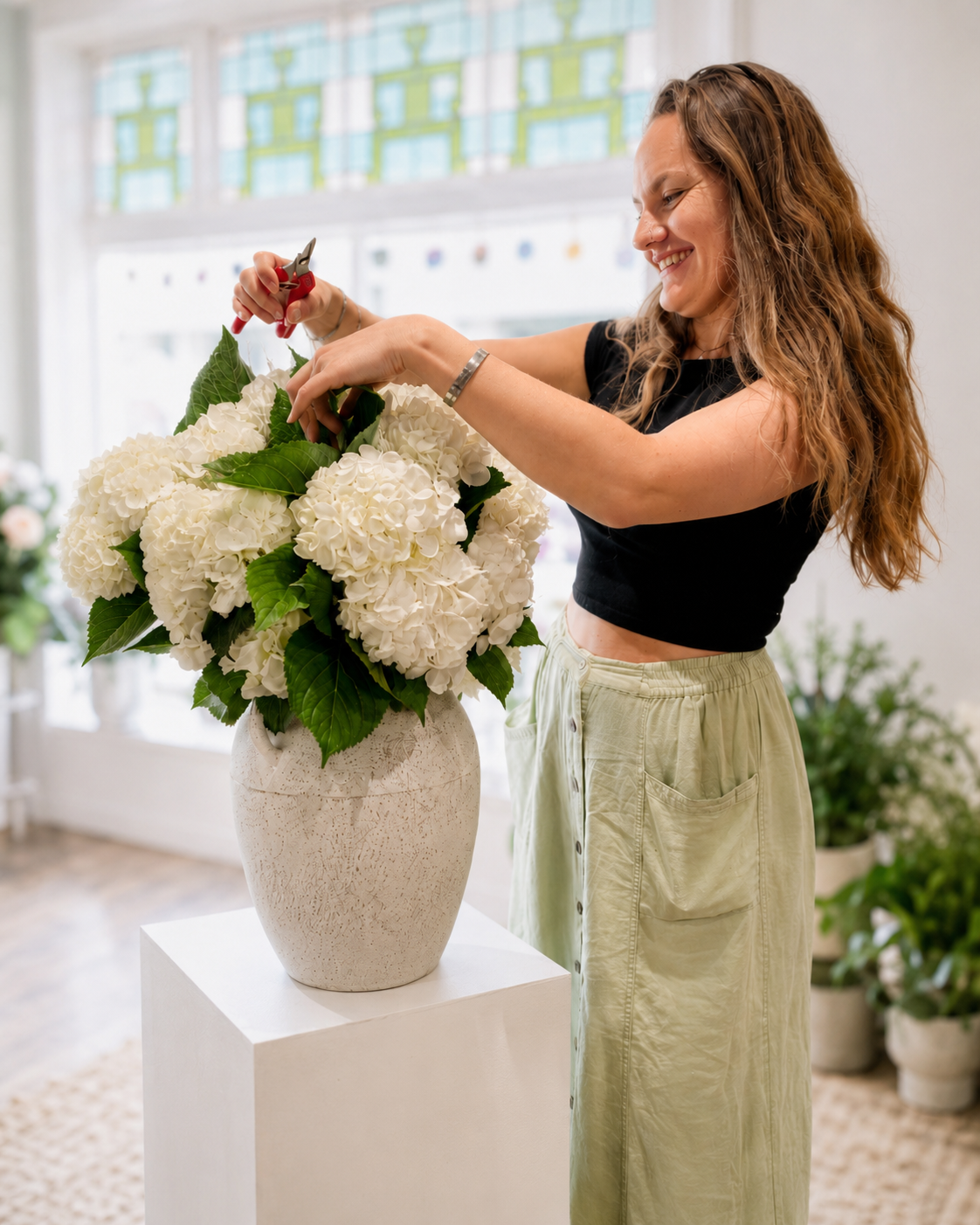 Woman arranging flowers in a large vase indoors