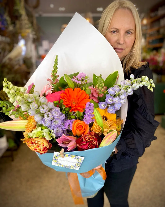 Woman holding a large fresh flower bouquet of bright mixed colours