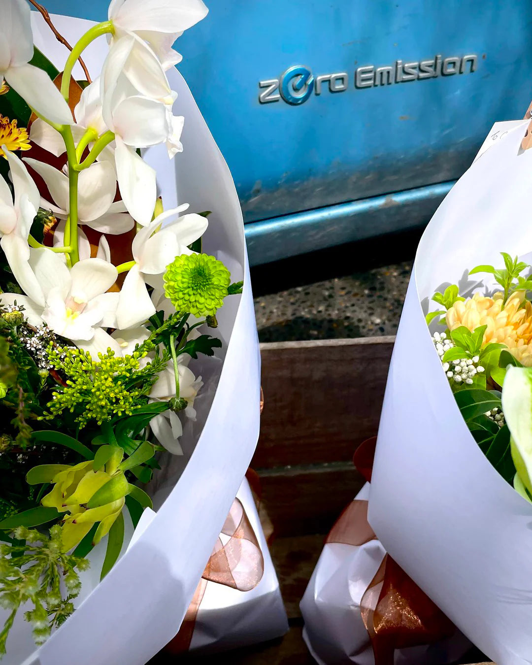 Two fresh flower bouquet in front of an electric delivery vehicle