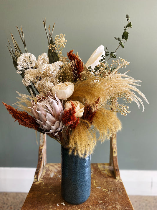 Dried flower arrangement in a glazed ceramic vase